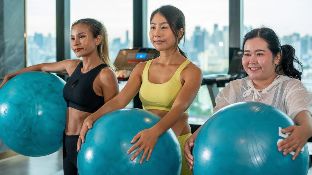 Humor in sports Ball Yoga. Fat Asian woman with her Yoga Instrutor teacher