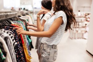 Two young smiling slim girls with long dark hair,wearing casual style,have shopping in a modern mall