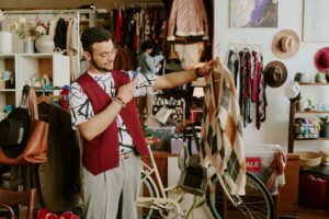 Young Man Admiring Sweater in Cozy Secondhand Shop